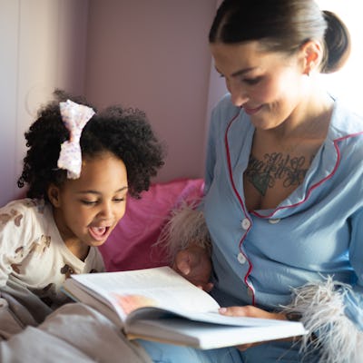 Mom and little kid read book in bed.