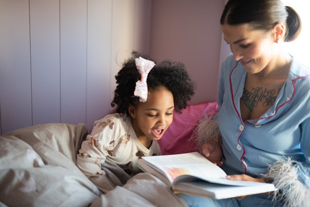 Mom and little kid read book in bed.