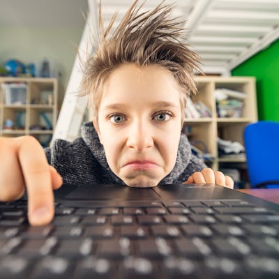 Teenage boy using laptop as seen directly from the screen. The boy's face shows boredom, as he types on the keyboard.
Shot with Canon R5
