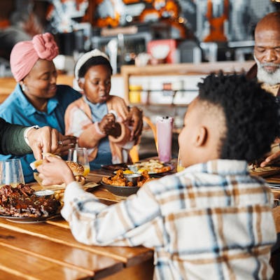 Black family, restaurant and food share with dad and child together with bonding, eating and care. Love, diner and table with burgers and happy girl with lunch and hungry people in a cafe with drink