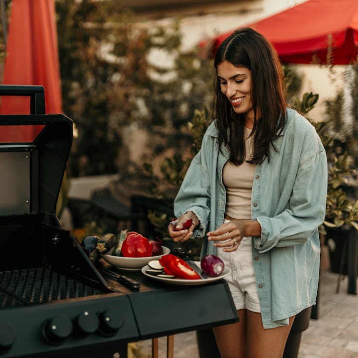 Smiling woman cutting the veggies and preparing it for a BBQ