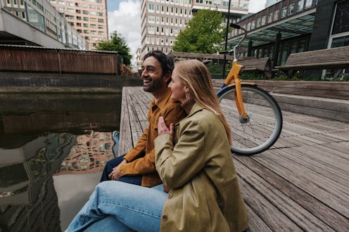 Young couple sitting by a canal in Rotterdam, Netherlands, enjoying a relaxing moment together