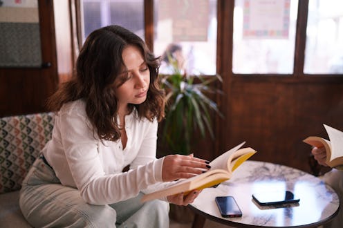 A young woman reads in a coffee shop, enjoying a quiet moment away from the hustle of daily life. Th...