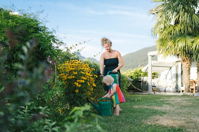 Mother and baby girl water plants in back yard, Lugano, Ticino