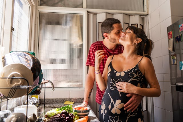 Husband kissing pregnant wife at home