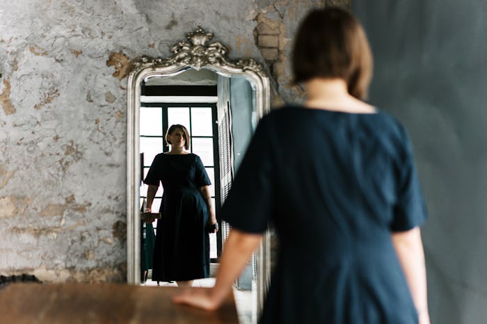 Reflection of a woman's face in mirror pieces on a wooden wall. Portrait of an emancipated businessw...