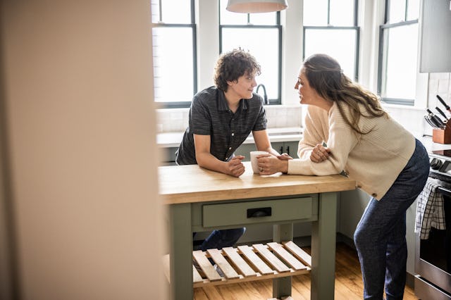 Mother and teenage son talking in kitchen