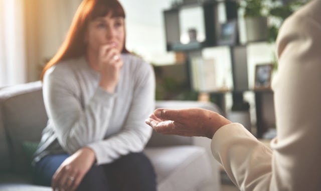 A woman talking to a psychologist or therapist. A young woman looking sad while getting help during ...