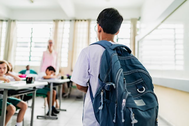 Student carrying backpack arriving on the classroom in the school