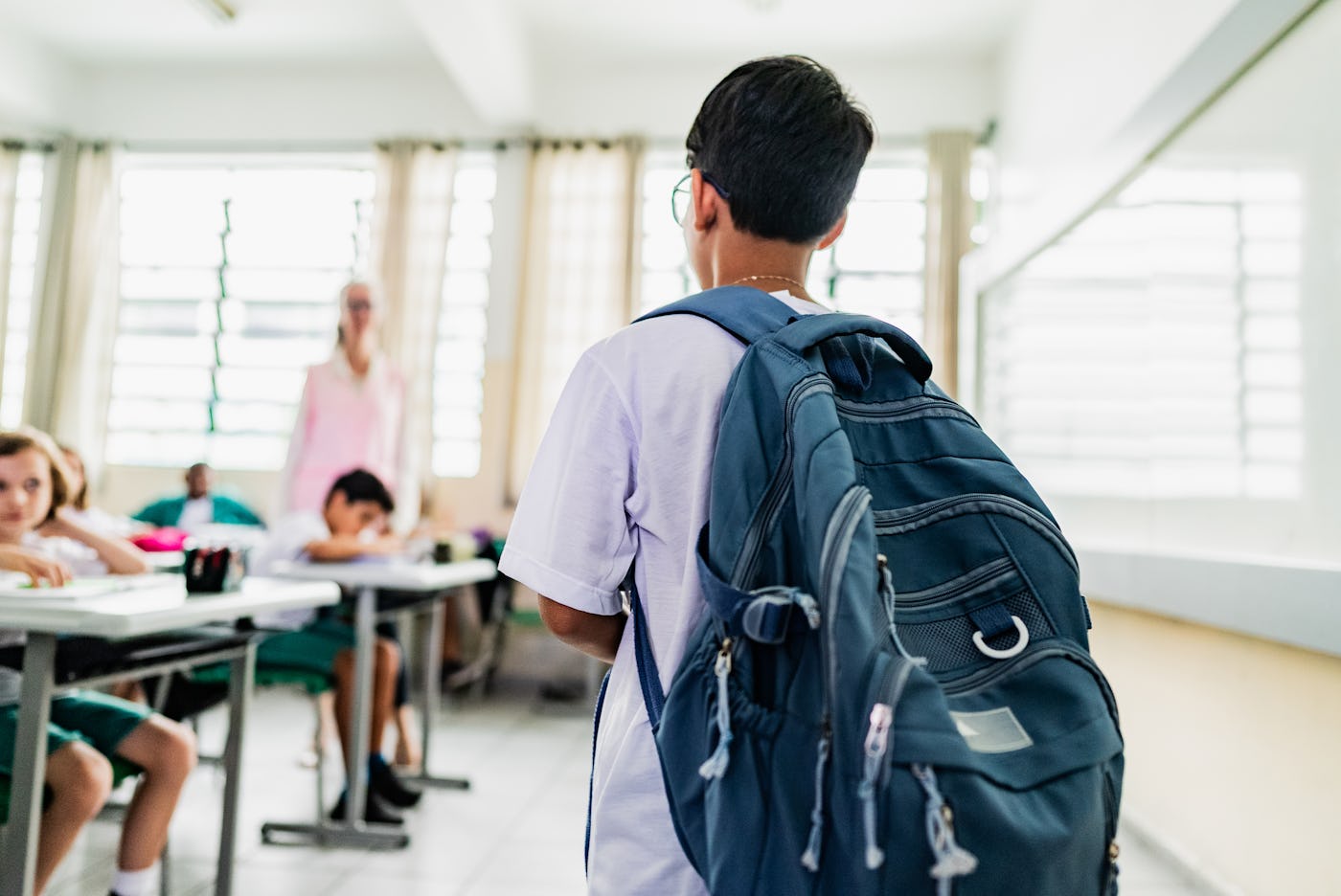 Student carrying backpack arriving on the classroom in the school