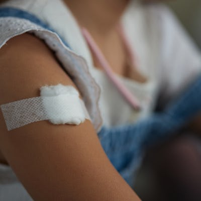 Child with bandage on arm after vaccine.
