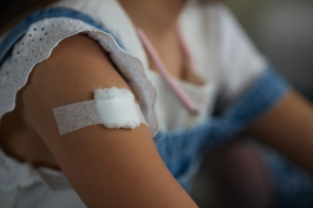 Child with bandage on arm after vaccine.
