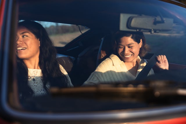 Two friends on vacation traveling Southern California with a vintage car on coastal winding roads.
