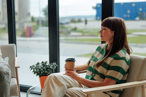 Young woman enjoying a moment of peace while sipping coffee in a cafe, looking outside the window