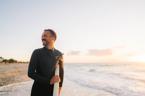 Photo of a male surfer at the beach, holding his surfboard