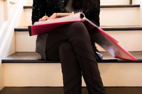 female student with hair scrunchie on wrist sits with school ring binder open