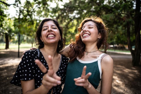 Portrait of sisters making peace sign in a public park