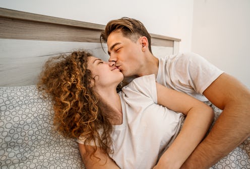 Young loving couple kissing in bed in the morning, enjoying intimacy and sharing a tender moment