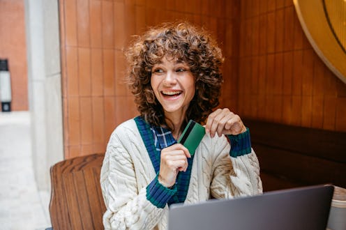 Beautiful young woman shopping online using laptop in a sidewalk café after in Shanghai in China.