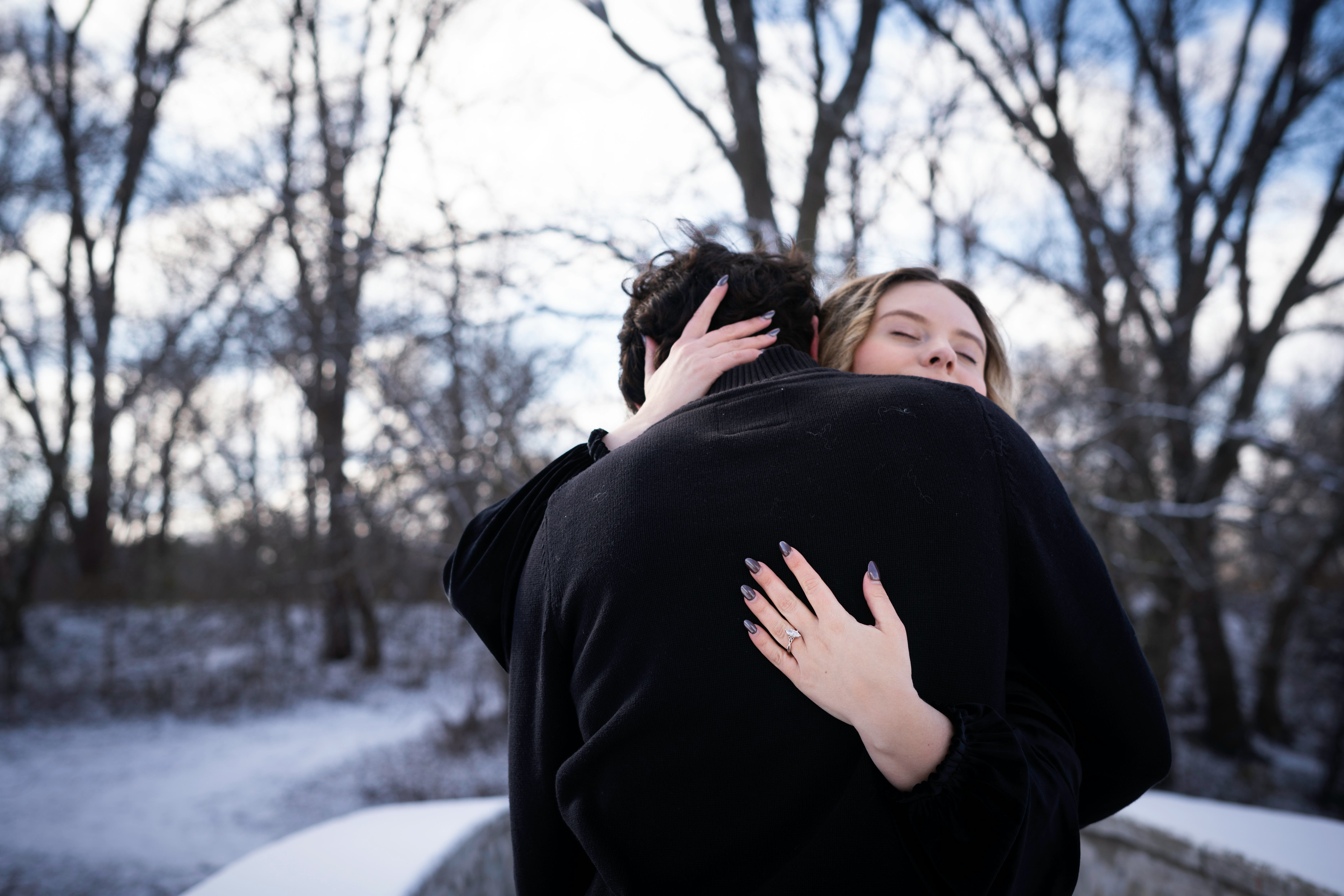 Happy engaged couple affectionately hugging standing outdoors on a snowy cold day, Rochester, Minnes...