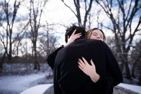 Happy engaged couple affectionately hugging standing outdoors on a snowy cold day, Rochester, Minnes...