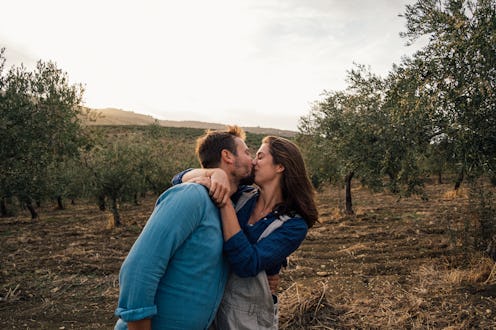 A couple sharing a romantic moment together in a scenic olive grove during sunset, capturing relaxat...