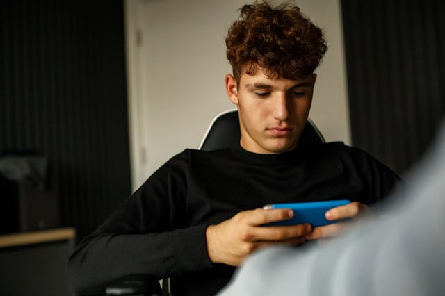 A 14-year-old girl is using her smartphone in the dark room.