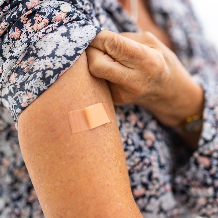 Close-up of a bandage on the arm of a female after getting coronavirus vaccine in the clinic. Female...