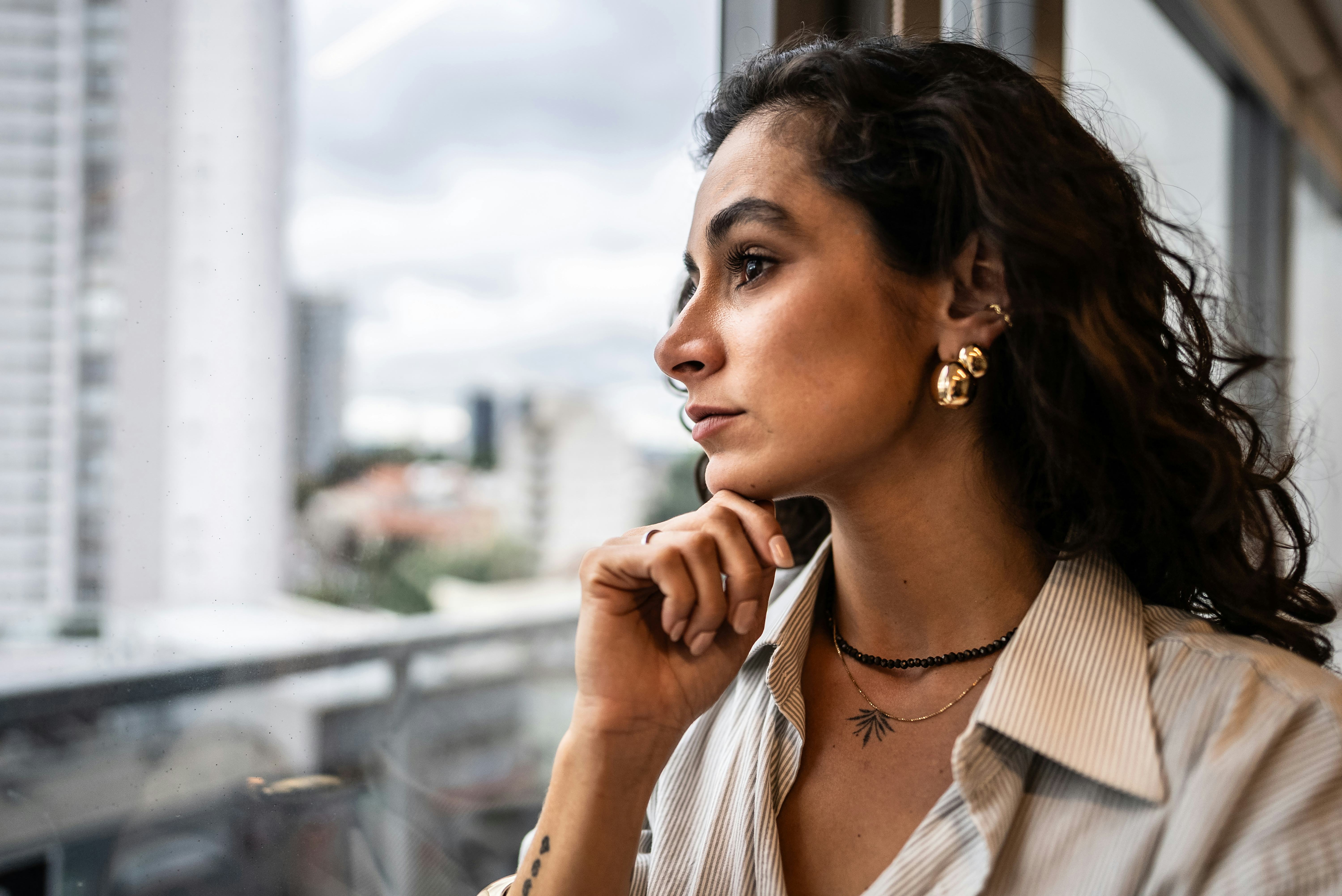 Pansexual businesswoman contemplating looking through the window at the office