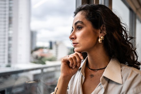 Pansexual businesswoman contemplating looking through the window at the office