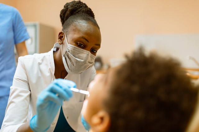A dentist performs a routine dental checkup on a young patient.