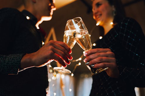 Young couple toasting with champagne flutes on new year's eve, surrounded by festive string lights