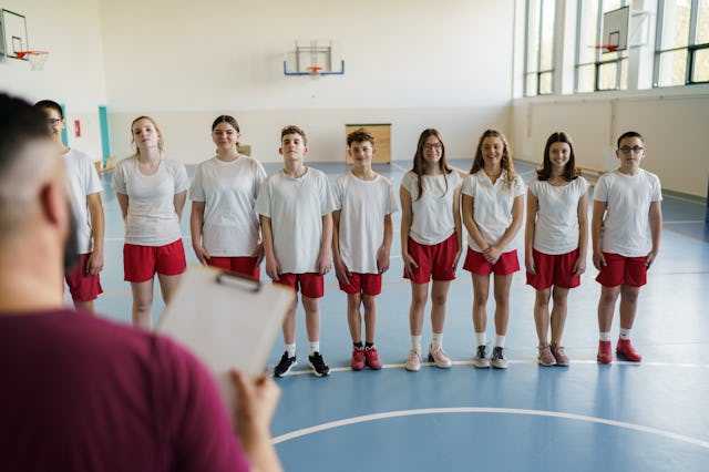 Group of teenage children standing in a row on sports training whit their trainer