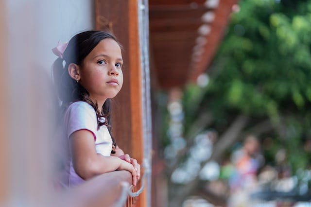 A Latina girl from Bogota, Colombia, between 10 and 14 years old, looks out from the balcony of her ...
