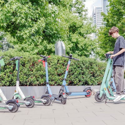 A teenage boy going to rent an e-scooter in the city park.