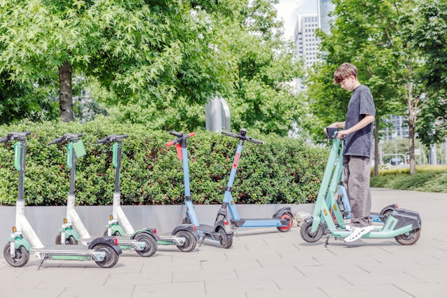 A teenage boy going to rent an e-scooter in the city park.