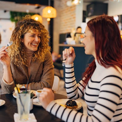 Two female best friends gathered in a coffee shop to drink coffee and eat delicious cakes
