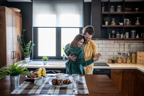 Young couple dancing in their modern kitchen, enjoying a carefree moment together as they embrace an...
