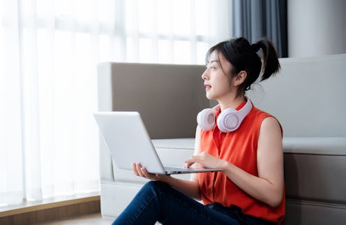 The woman sitting on floor and using laptop