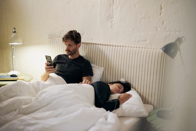 Online shopping, couple and man with smartphone, bedroom and searching for gift on website or valent...