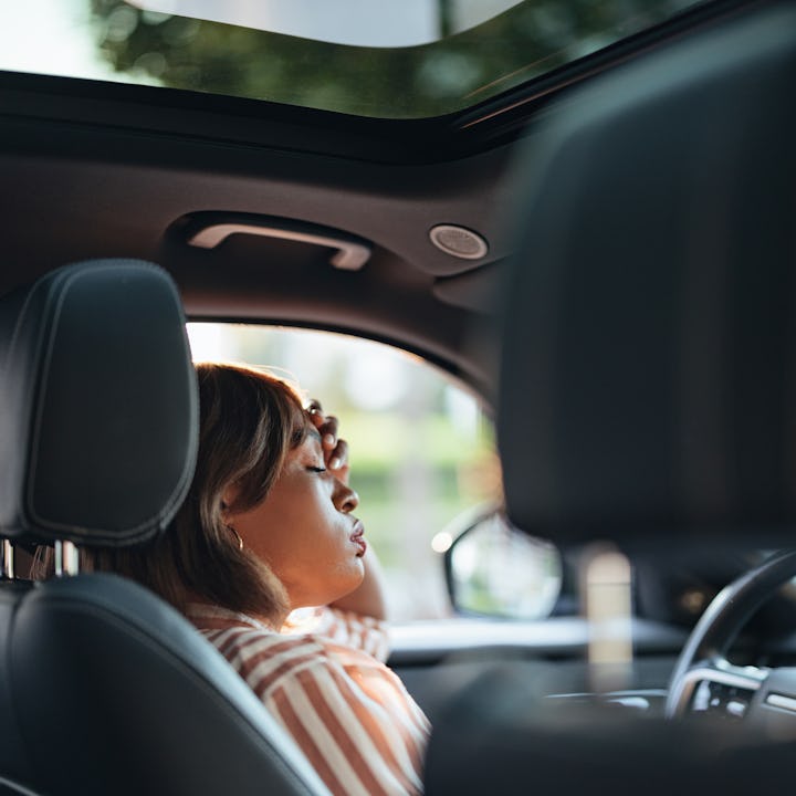 A focused African American businesswoman is seen driving a car in a city setting, capturing a moment...