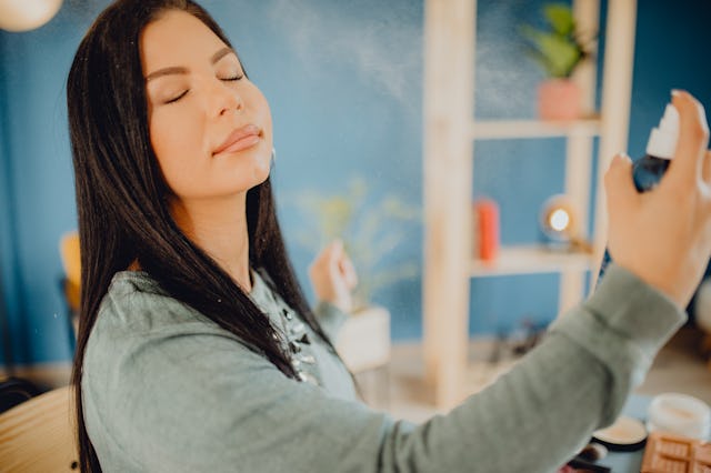A young Caucasian woman applying the setting spray to her face.
