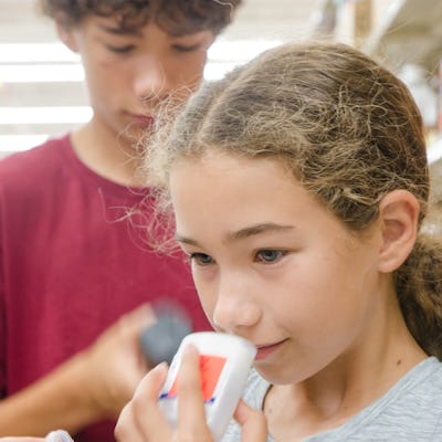 Teenager girl smelling a deodorant while brother is looking at another one in a store.