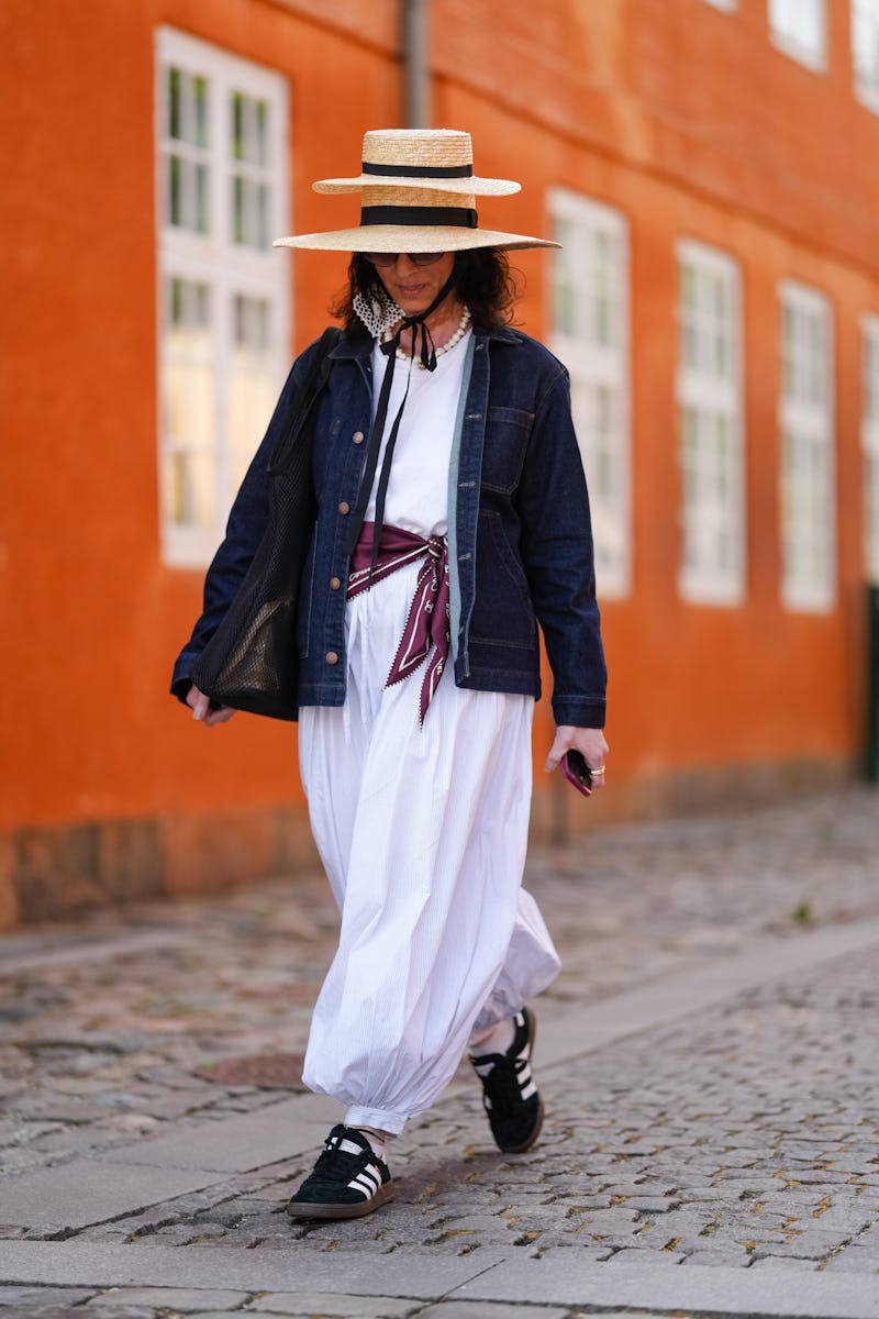 COPENHAGEN, DENMARK - AUGUST 05: A guest wears a double wide-brimmed straw hat with a black ribbon d...