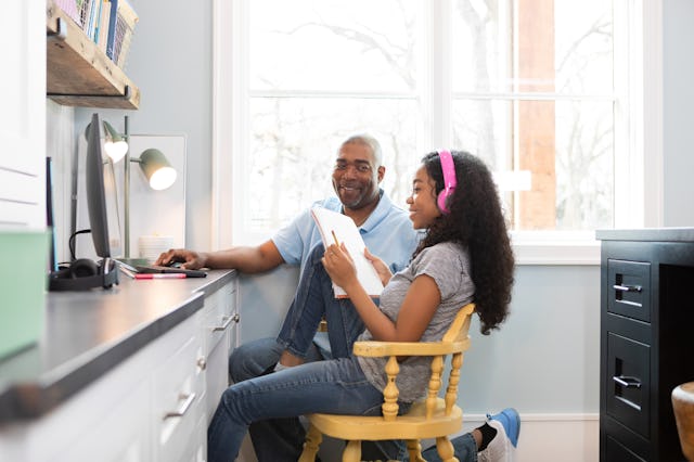 A father helps his teenage daughter with her homework.