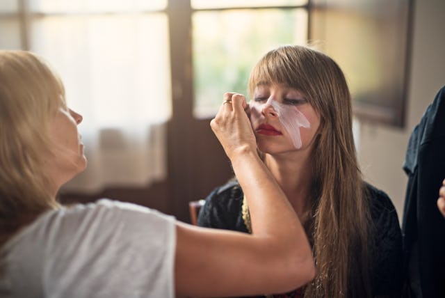 Teenage girl preparing for Halloween. Mother is applying make up on the daughter's face.
Nikon D810