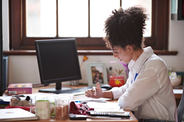 Side view of female professor using smart phone while sitting at desk in classroom