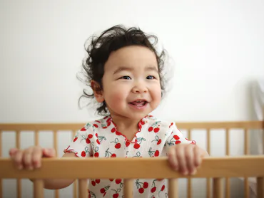 A baby girl smiling in her bedroom
