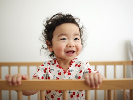 A baby girl smiling in her bedroom