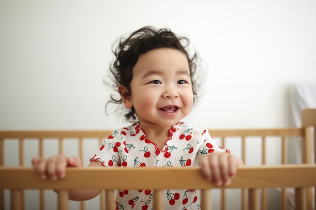 A baby girl smiling in her bedroom